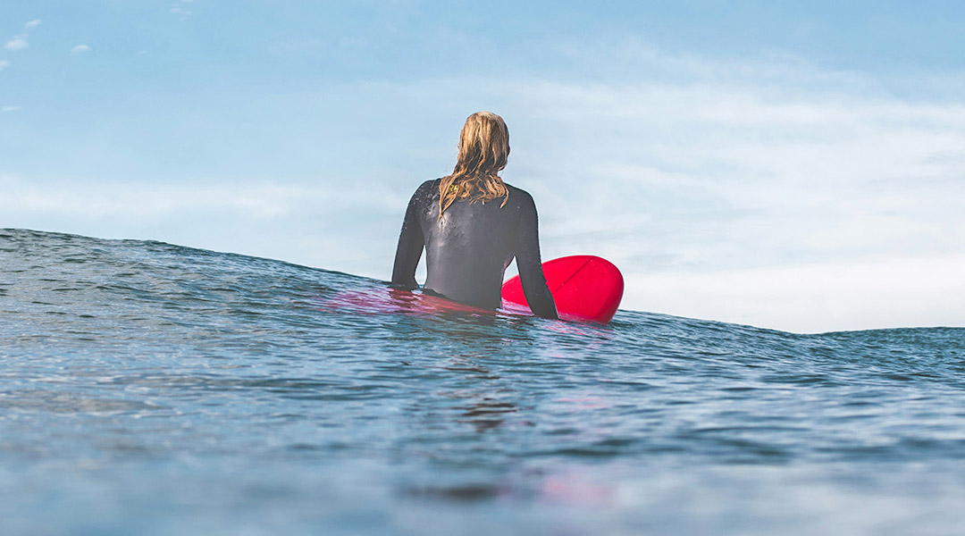 material zum surfen - surferin im wasser auf rotem board