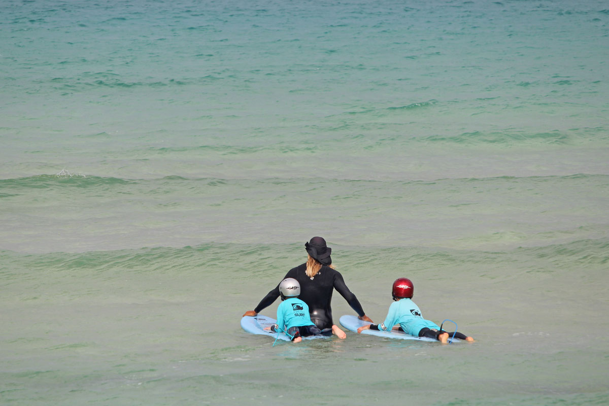 wassersicherheit für kinder - surfcoach mit zwei kindern im seichten wasser